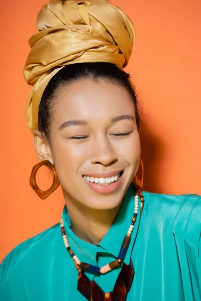 Portrait of positive african american woman in summer clothes and headband on orange background — Stock Photo