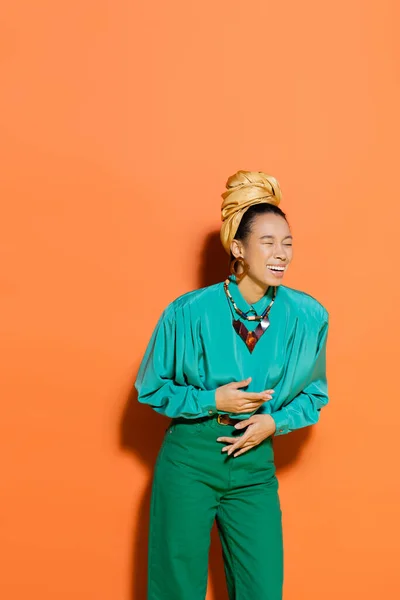 Elegante modelo afroamericano riendo sobre fondo naranja - foto de stock