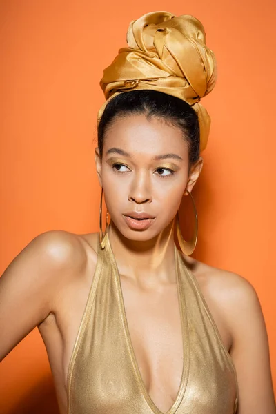 Модная африканская модель в платке и купальнике, стоящая на оранжевом фоне — стоковое фото