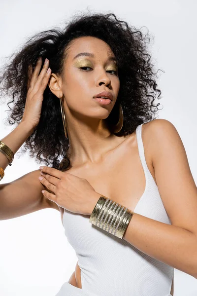 Modelo afroamericano de moda en vestido y accesorios mirando a la cámara aislada en gris - foto de stock