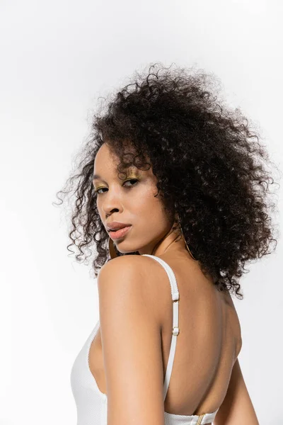 Modèle afro-américain aux cheveux bouclés posant en maillot de bain blanc isolé sur gris — Photo de stock