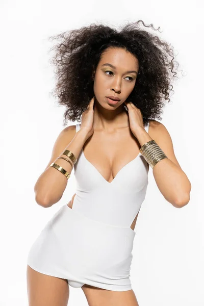 Joven modelo afroamericano con pulseras doradas en las manos posando en traje de baño aislado en blanco - foto de stock