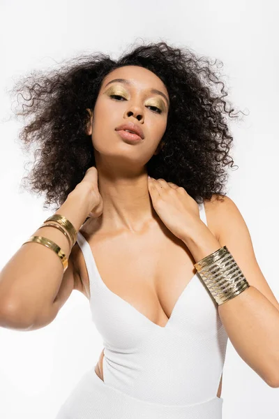 Молода афроамериканська модель з золотими браслетами на руках позує в купальнику ізольована на білому — стокове фото