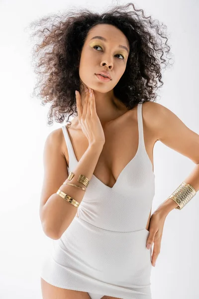 Portrait of young african american model with curly hair posing with hand on hip isolated on grey — Stock Photo