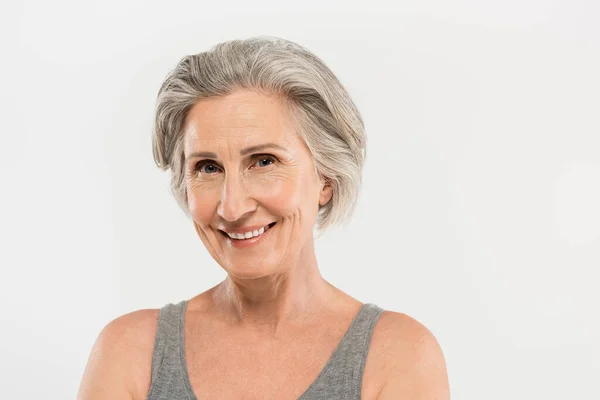 Portrait of happy senior woman smiling and looking at camera isolated on grey — Stock Photo