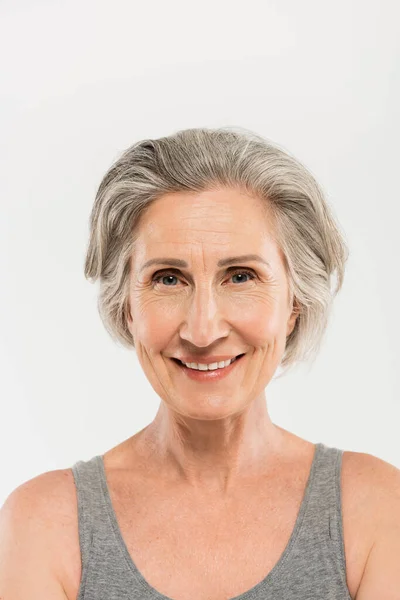 Portrait of overjoyed senior woman smiling and looking at camera isolated on grey — Stock Photo