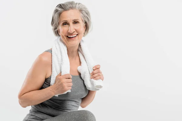 Glückliche Seniorin mit weißem Handtuch und Blick auf Kamera isoliert auf grau — Stockfoto