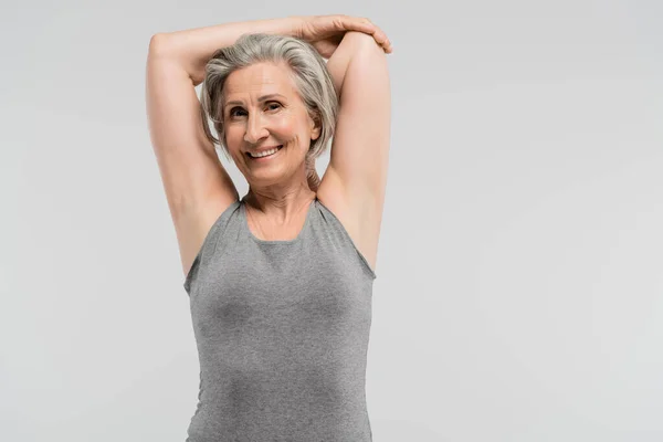 Compiaciuta nonna in abbigliamento sportivo allenarsi e sorridere isolata sul grigio — Foto stock