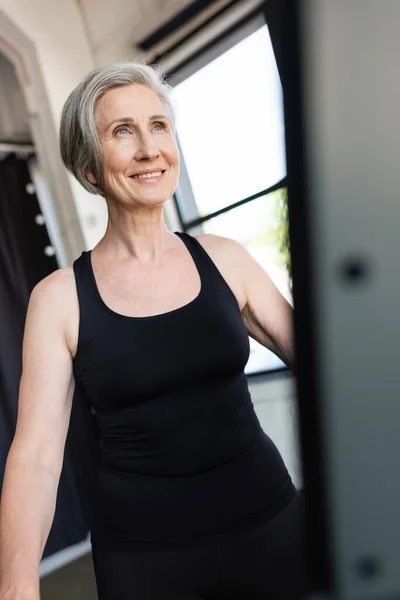 Cheerful senior woman with grey hair exercising in sports center — Stock Photo