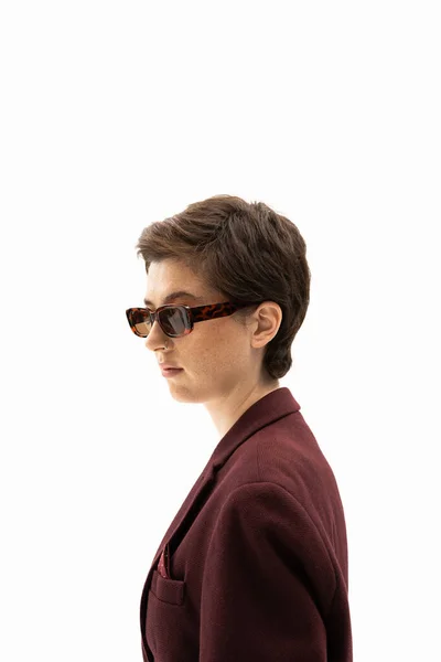 Vista lateral de mujer con pelo corto morena usando gafas de sol de moda aisladas en blanco - foto de stock