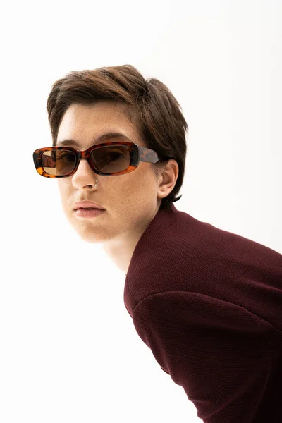 Brunette woman in trendy sunglasses and brown blazer looking at camera isolated on white — Stock Photo