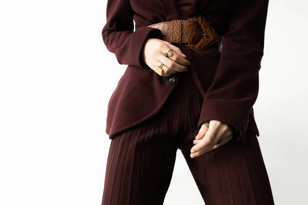 Vista parcial de la mujer con estilo en traje de pantalón marrón y cinturón de cuero sobre fondo blanco - foto de stock
