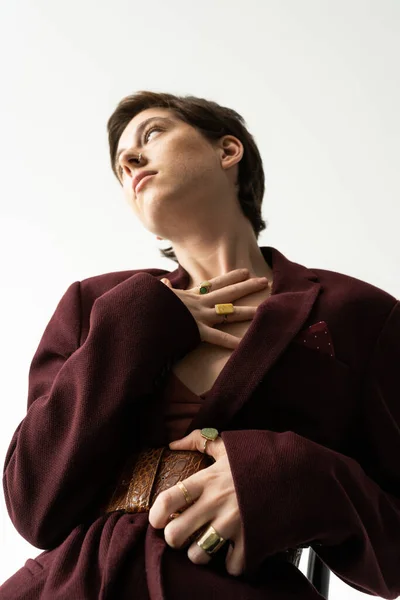 Vista de ángulo bajo de la mujer de ensueño en traje de primavera de moda mirando hacia otro lado sobre fondo gris - foto de stock