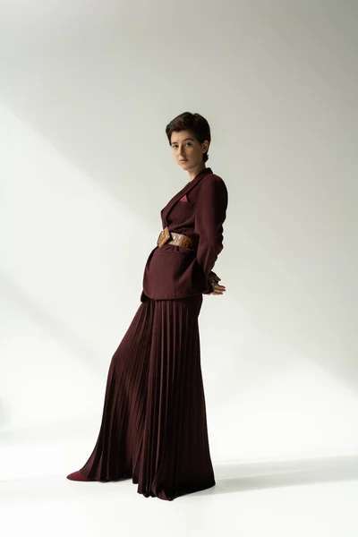 Full length of young model in blazer and palazzo pants looking at camera on grey background with lighting — Stock Photo