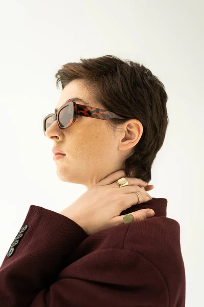 Brünette Frau mit trendiger Sonnenbrille und Fingerringen, die isoliert von grau wegschaut — Stockfoto