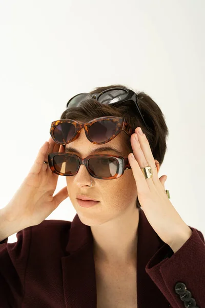 Portrait of trendy woman wearing different fashionable sunglasses isolated on grey — Stock Photo