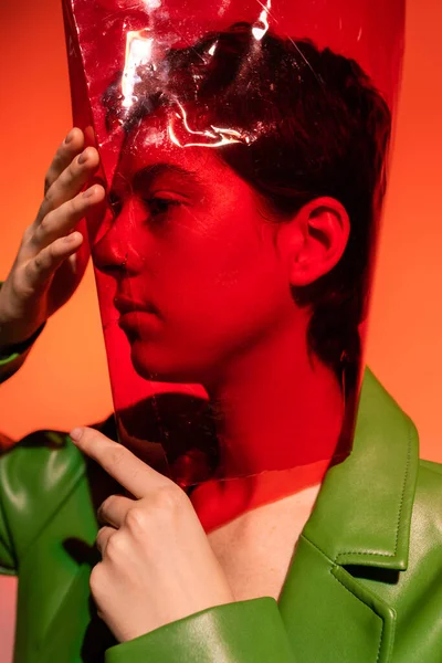 Молодая брюнетка женщина покрывает голову с прозрачной формы цилиндра пластика на оранжевом фоне — стоковое фото
