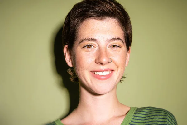 Portrait of carefree and freckled woman smiling at camera on green background — Stock Photo