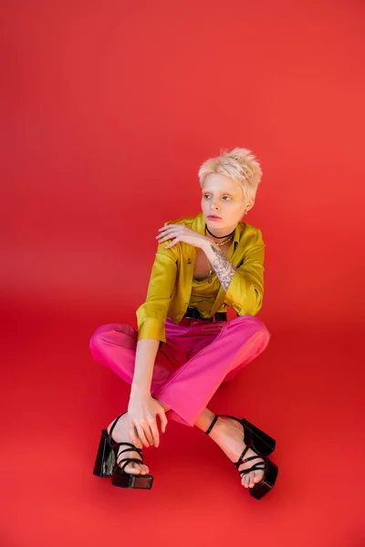 Junges Albino-Model in trendiger Kleidung posiert auf karminrosa — Stockfoto