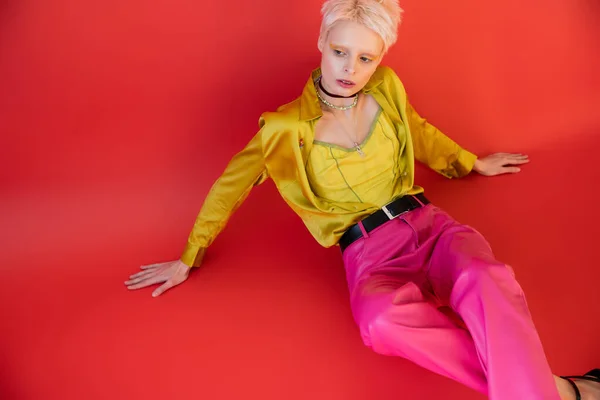 Vue grand angle du jeune modèle albinos en vêtements tendance posant sur rose carmin — Photo de stock