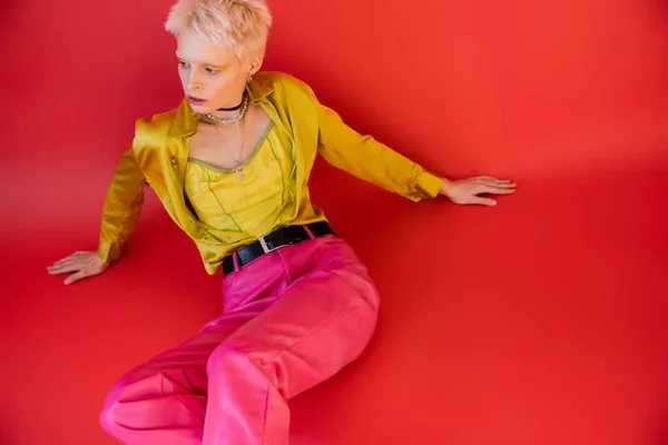 High angle view of blonde albino model in trendy clothes posing on carmine pink — Stock Photo