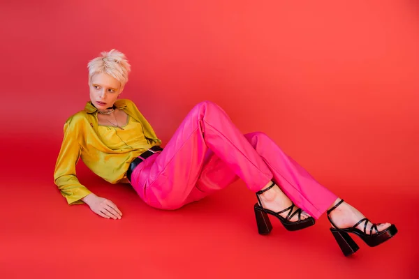 Полная длина альбиноса женщина в сандалиях на каблуках и модная одежда позирует на кармине розовый — стоковое фото