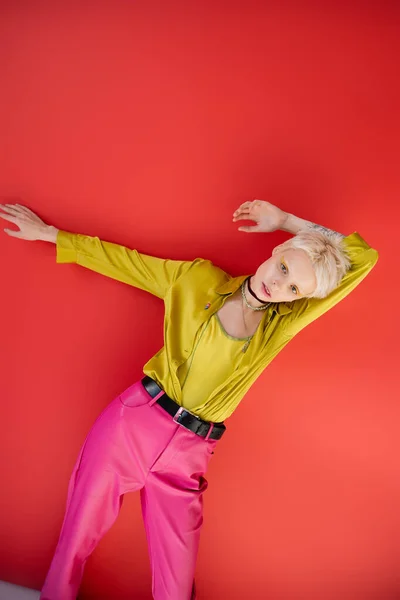 Блондинка-альбиноса с светлыми волосами и татуированной рукой, позирующей на кармине розового цвета — стоковое фото