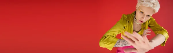 Overhead view of albino woman with tattoo looking at camera while posing on carmine pink background, banner — Stock Photo