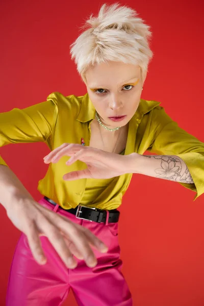 High angle view of albino woman with tattoo looking at camera while posing on carmine pink — Stock Photo