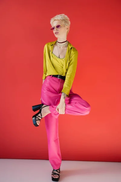Полная длина модели альбиноса с татуированной рукой позируя в стильных сандалиях на каблуках на кармине розовый — стоковое фото