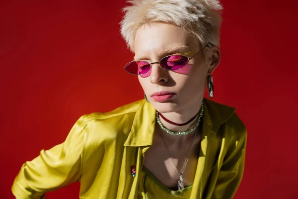 Солнечный свет на лице модели альбиноса в стильных солнцезащитных очках на розовом фоне — стоковое фото