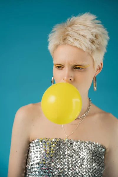 Stylish albino woman with bare shoulders blowing bubble gum on blue background — Stock Photo