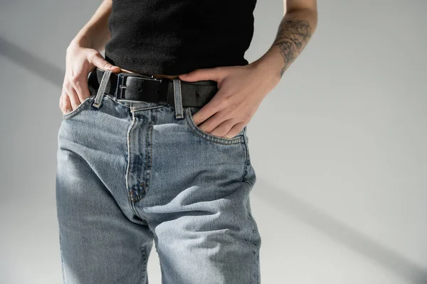 Vue recadrée d'une femme en jeans denim posant sur fond gris — Photo de stock