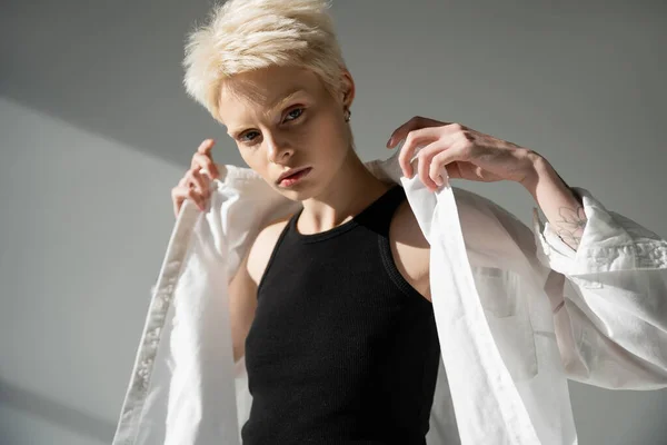 Женщина-альбинос в черном топе в белой рубашке на сером фоне — стоковое фото
