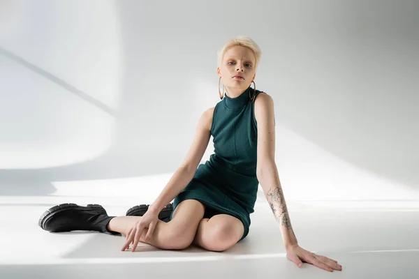 Volle Länge der hübschen Albino-Frau in engem Kleid und Stiefeln posiert auf grauem Hintergrund mit Schatten — Stockfoto