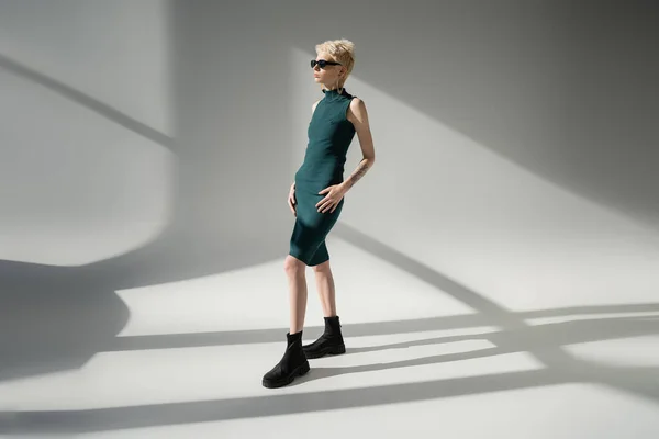 Volle Länge des tätowierten Modells mit heller Haut posiert in Stiefeln und Kleid auf grauem Hintergrund — Stockfoto