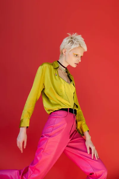 Blondine mit hellem Eyeliner posiert in stylischem Outfit auf karminrosa Hintergrund — Stockfoto