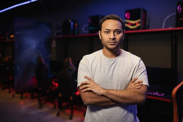 Indian gamer crossing arms and looking at camera in gaming club — Stock Photo