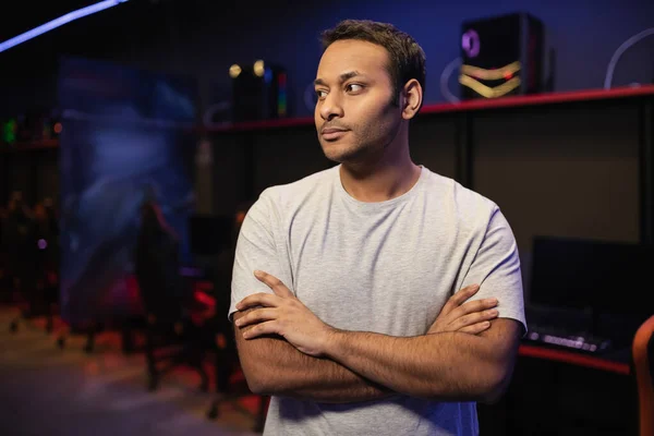 Indian gamer crossing arms and looking away in cyber club — Stock Photo