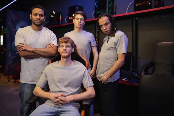 Equipe de gamer multiétnico em camisetas cinza olhando para a câmera no clube cibernético — Fotografia de Stock