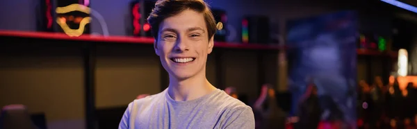 Porträt eines positiven jungen Mannes, der in eine Kamera in einem Spielklub blickt, Banner — Stockfoto
