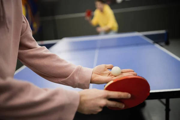 Vista recortada del hombre sosteniendo raqueta y pelota mientras juega al tenis de mesa en el club de juego - foto de stock