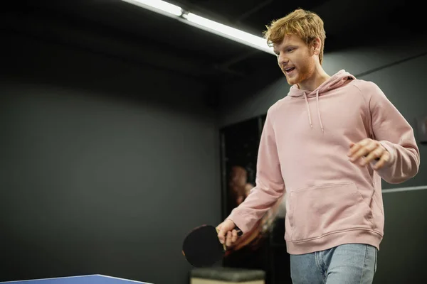 Uomo rosso spensierato che gioca a ping pong nel club di gioco — Foto stock