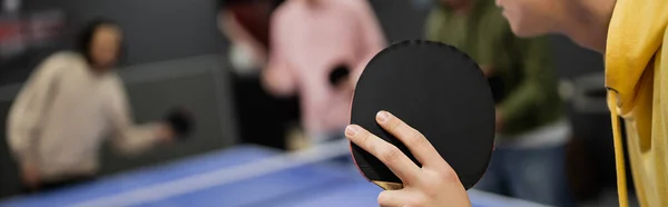 Cropped view of man playing table tennis with blurred friends in gaming club, banner — Stock Photo