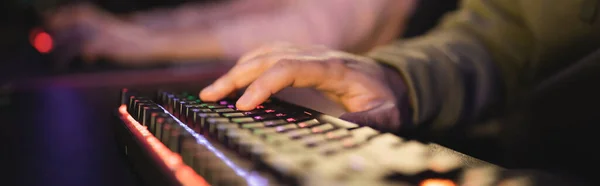 Vista recortada del hombre utilizando el teclado en el club cibernético, bandera - foto de stock