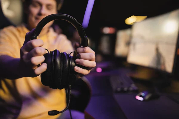 Blurred man holding headphones with microphone in gaming club — Stock Photo