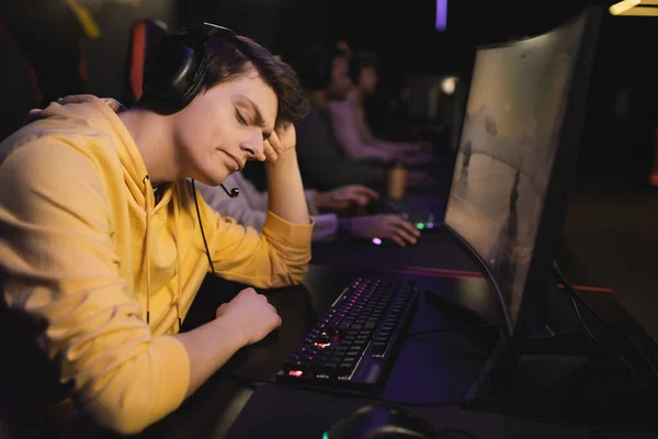 Displeased gamer in headphones sitting near computer in gaming club — Stock Photo