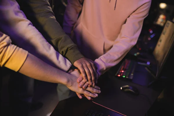 Cropped view of interracial friends holding hands in gaming club — Stock Photo