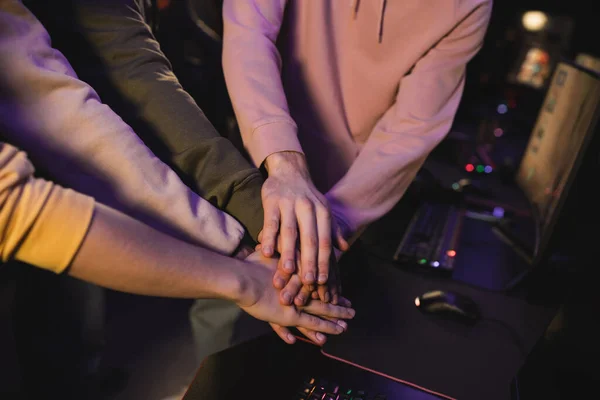 Обрезанный вид многонациональной команды, держащейся за руки в кибер-клубе — стоковое фото
