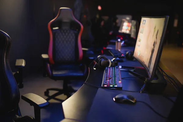 Computer monitors and keyboards on table in blurred gaming club — Stock Photo